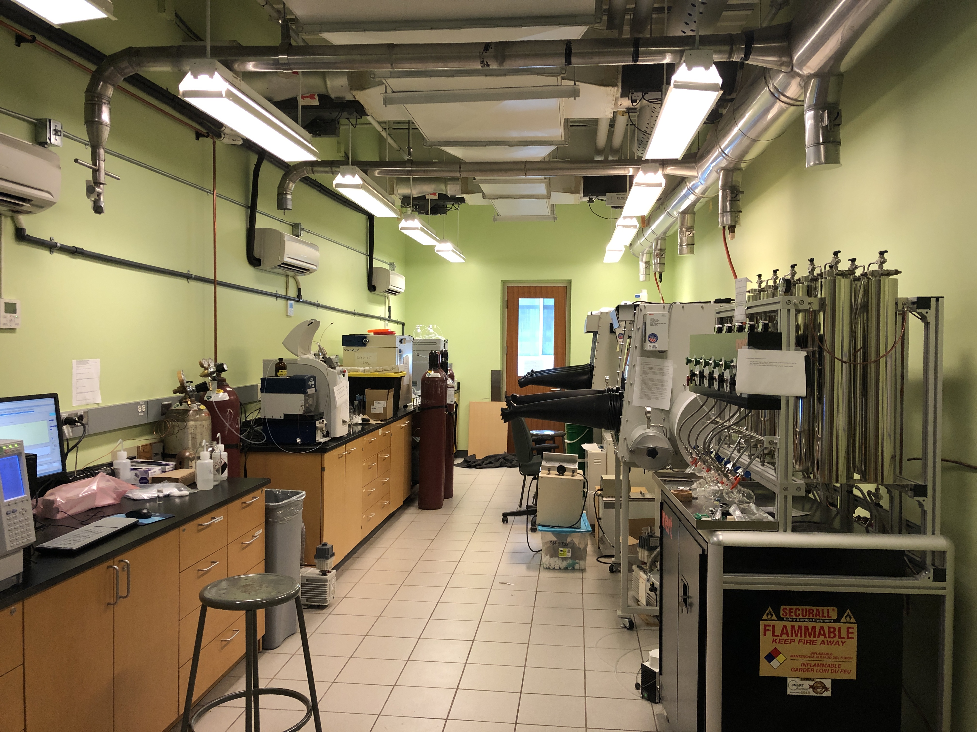 Standing in the doorway looking at the instrument room with benches on the left with equipment on top and gloveboxes on the right side